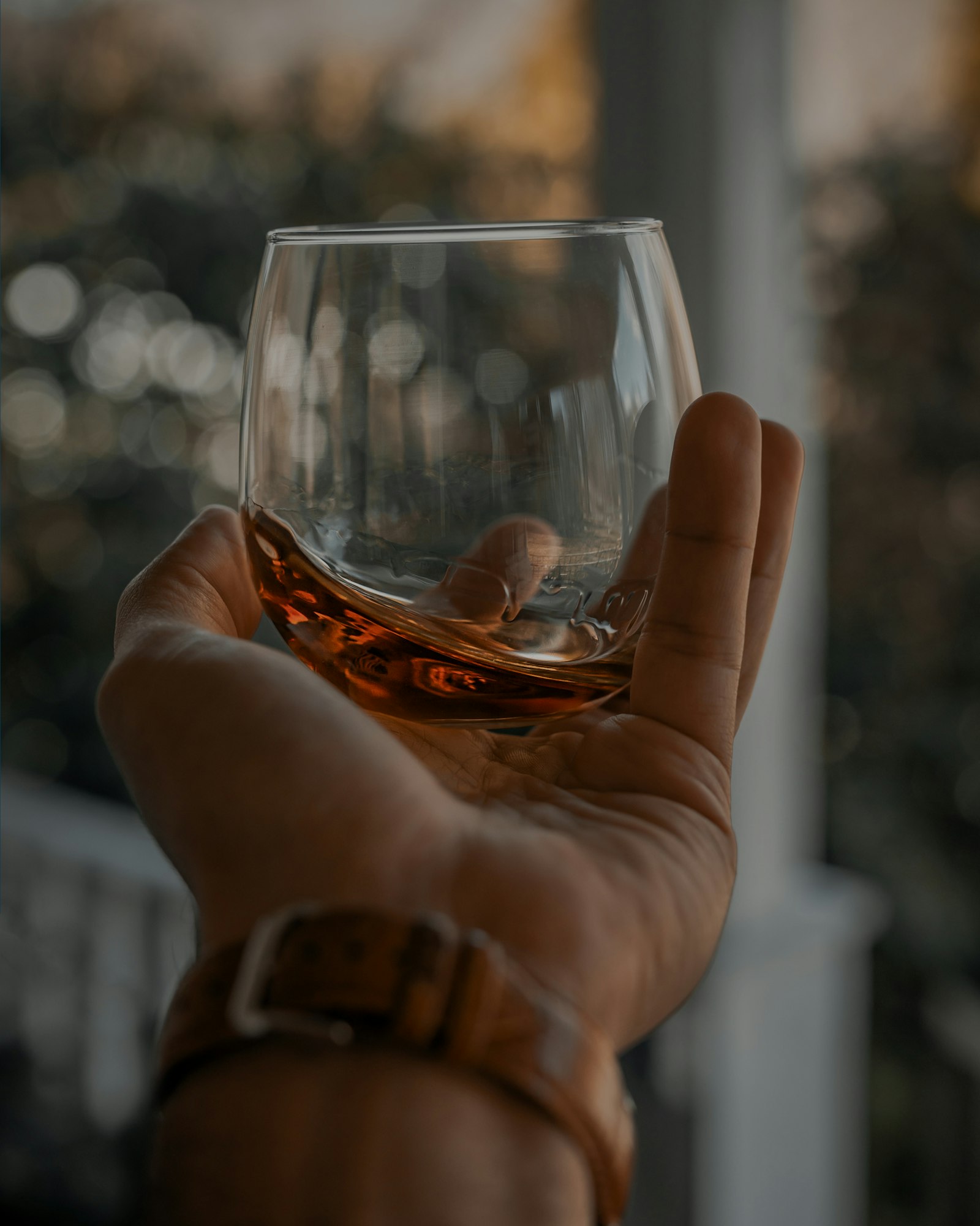 Kézben tartott whiskys pohár esti fényben
